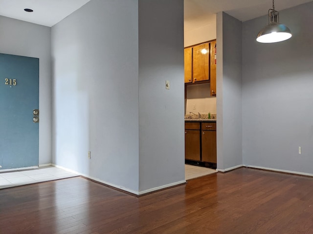 empty room with light wood-style floors, a sink, and baseboards