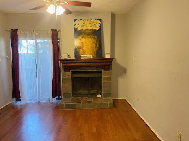 living room featuring a glass covered fireplace, wood finished floors, a ceiling fan, and baseboards