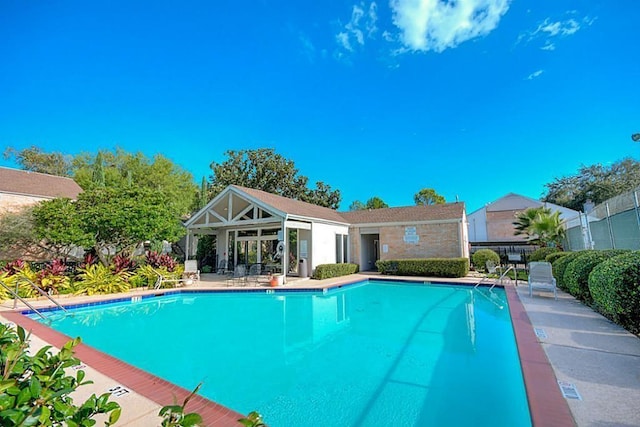 pool with a patio area and fence