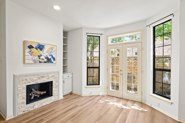 doorway with built in features, plenty of natural light, a fireplace, and wood finished floors