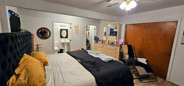 carpeted bedroom featuring a closet, visible vents, a sink, and ensuite bath