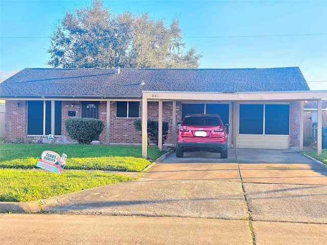 ranch-style house with concrete driveway, a front lawn, a shingled roof, and brick siding