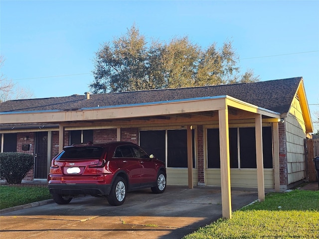 exterior space with a carport, concrete driveway, brick siding, and roof with shingles