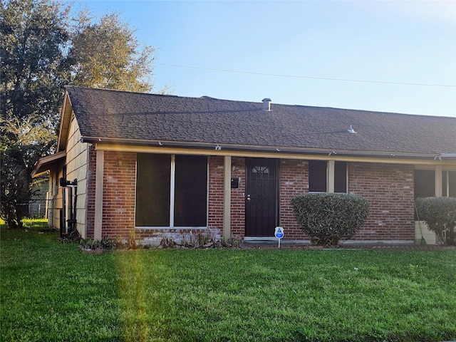 ranch-style house with roof with shingles, brick siding, and a front lawn