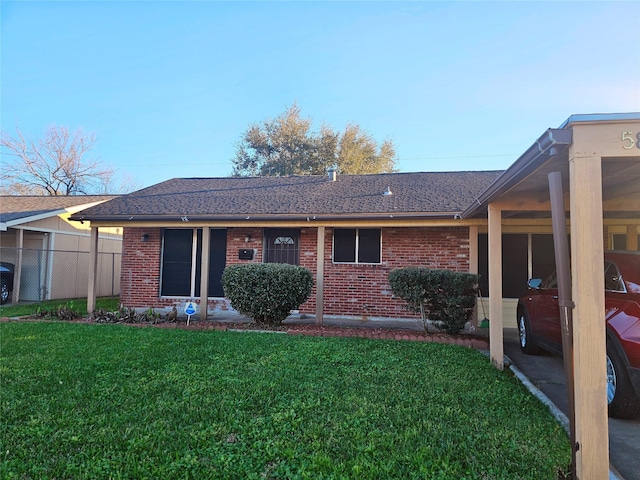 ranch-style house featuring brick siding, a front lawn, a shingled roof, and fence