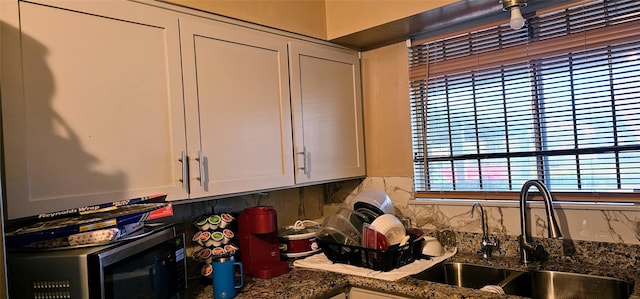 kitchen featuring dark stone countertops, decorative backsplash, and a sink