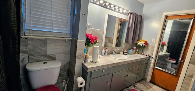 bathroom with vanity, toilet, and tile walls