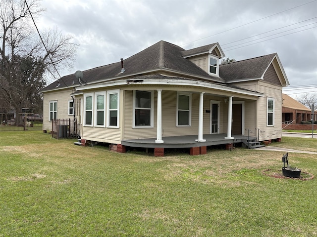 view of side of home featuring covered porch, a shingled roof, and a lawn