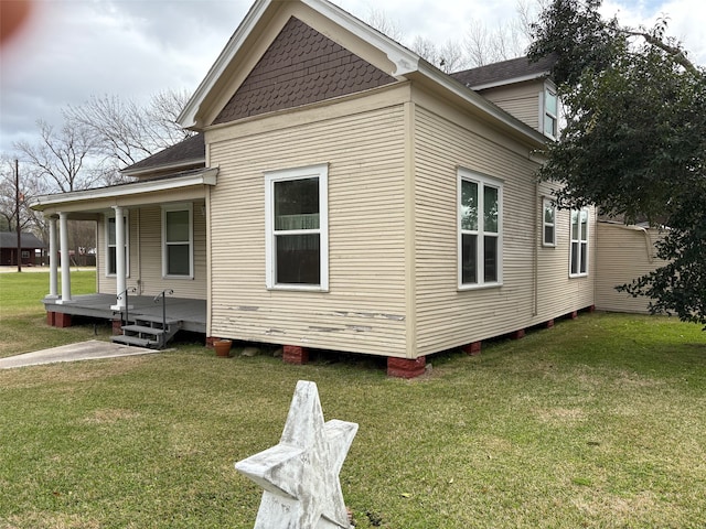 view of home's exterior featuring a yard, a porch, and roof with shingles