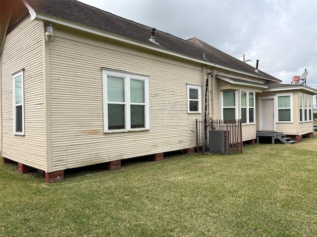 back of house featuring a shingled roof and a lawn