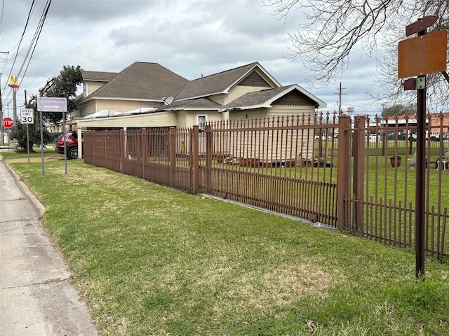 view of front of property featuring fence private yard, a shingled roof, and a front lawn