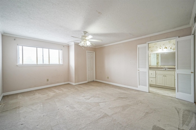 unfurnished bedroom with ornamental molding, light colored carpet, a textured ceiling, and baseboards