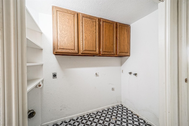 washroom featuring cabinet space, electric dryer hookup, a textured ceiling, baseboards, and tile patterned floors