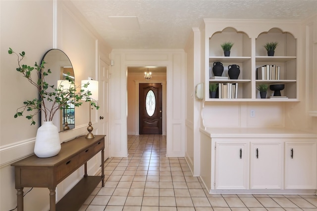 entryway featuring a textured ceiling, light tile patterned floors, and a decorative wall