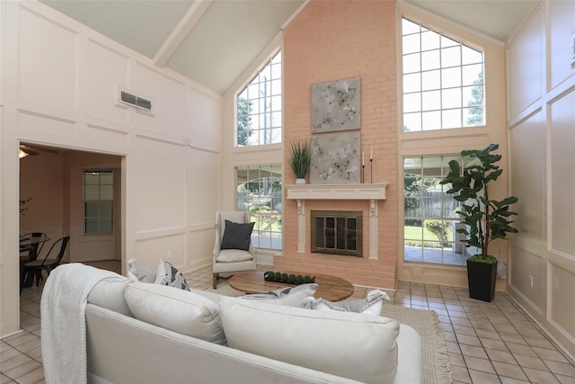 living room featuring a brick fireplace, a healthy amount of sunlight, a decorative wall, and light tile patterned floors