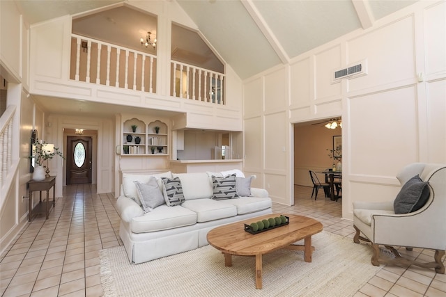 living room with light tile patterned floors, visible vents, a ceiling fan, high vaulted ceiling, and a decorative wall