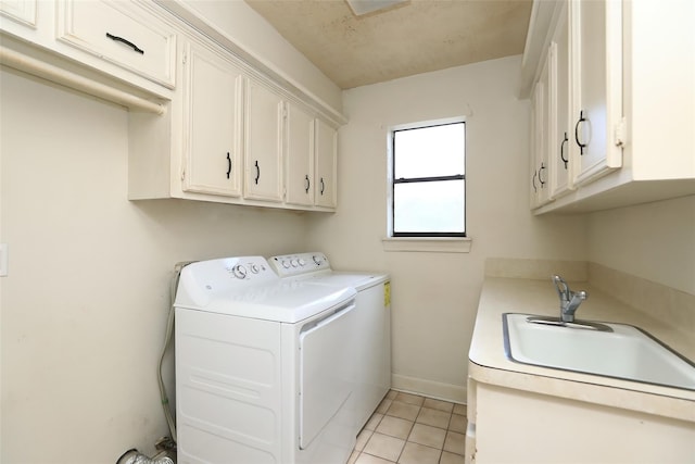 laundry room with washing machine and clothes dryer, light tile patterned floors, cabinet space, a sink, and baseboards