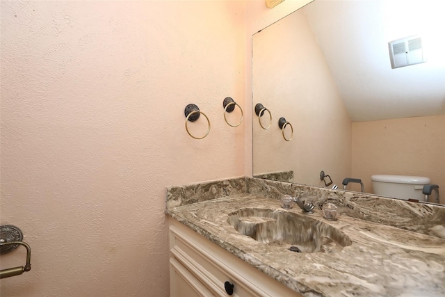 bathroom with visible vents, vaulted ceiling, vanity, and toilet