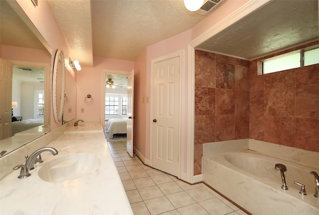 ensuite bathroom featuring connected bathroom, tile patterned floors, a garden tub, a textured ceiling, and a sink