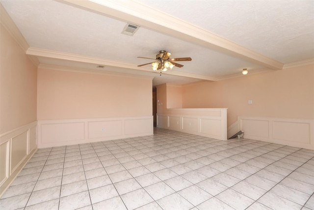 empty room with visible vents, a decorative wall, beamed ceiling, and ceiling fan