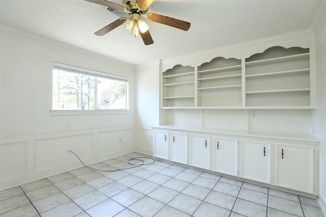 spare room with ornamental molding, a wainscoted wall, a decorative wall, and a ceiling fan