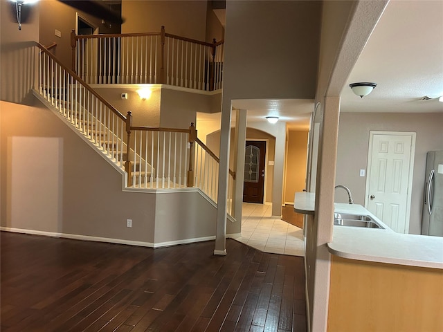 interior space featuring baseboards, wood-type flooring, stairway, a high ceiling, and a sink