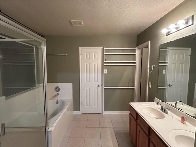 full bathroom featuring a textured ceiling, a sink, a bath, and tile patterned floors