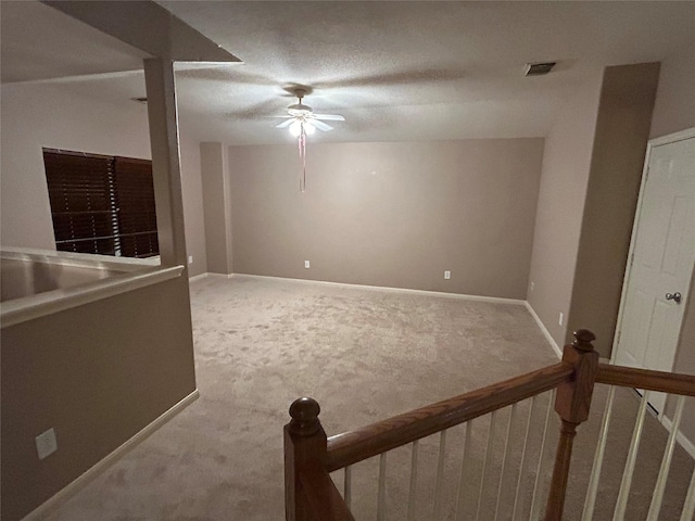 interior space featuring a ceiling fan, visible vents, a textured ceiling, and baseboards