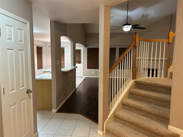 stairway with tile patterned flooring, visible vents, baseboards, and ceiling fan