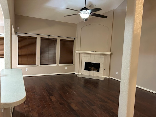 unfurnished living room featuring ceiling fan, a fireplace, baseboards, and dark wood-type flooring