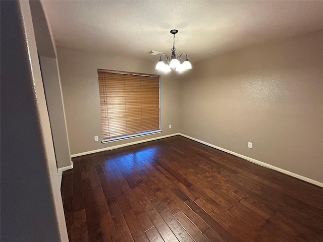 unfurnished room featuring baseboards, dark wood-style flooring, and a notable chandelier