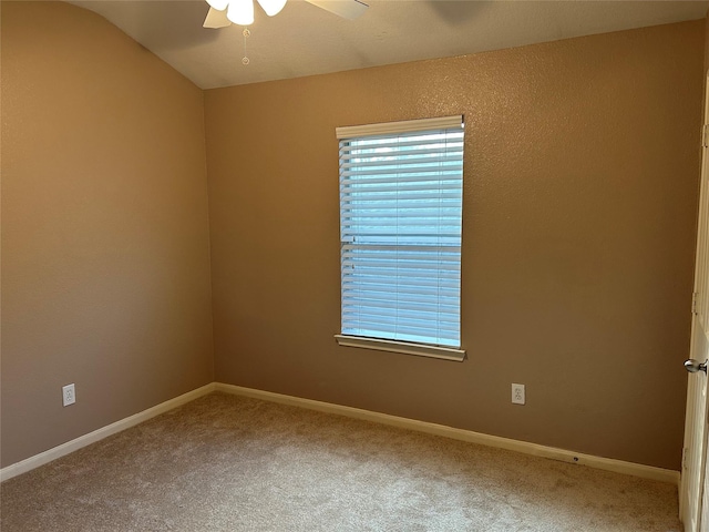 carpeted spare room with ceiling fan, vaulted ceiling, and baseboards