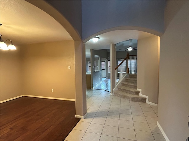 tiled entrance foyer with arched walkways, ceiling fan, baseboards, and stairs