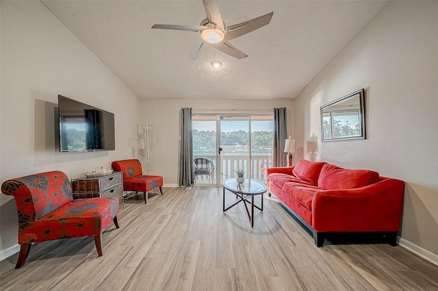 living room with vaulted ceiling, light wood finished floors, a ceiling fan, and baseboards