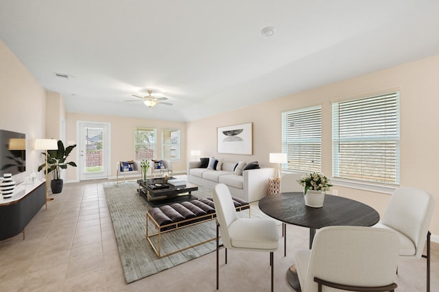 living area featuring light tile patterned floors, ceiling fan, visible vents, and baseboards