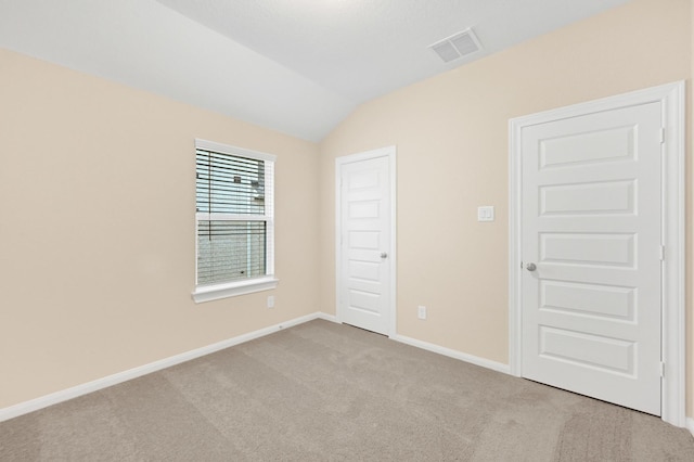 unfurnished room featuring lofted ceiling, baseboards, visible vents, and carpet flooring