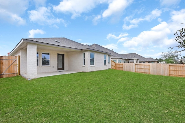 rear view of property featuring a fenced backyard, brick siding, a yard, roof with shingles, and a patio area