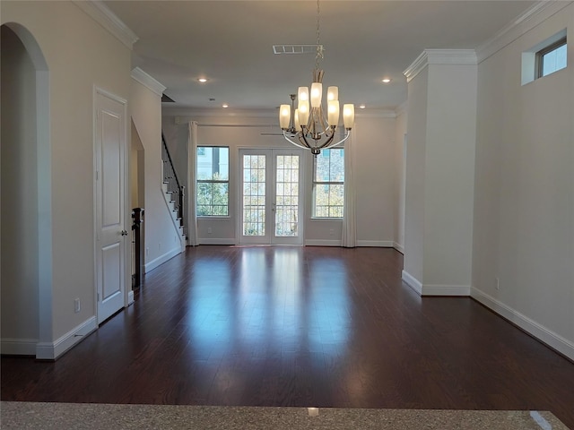 empty room with crown molding, visible vents, dark wood finished floors, and arched walkways