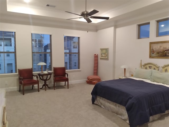 carpeted bedroom with a raised ceiling, visible vents, ceiling fan, and baseboards