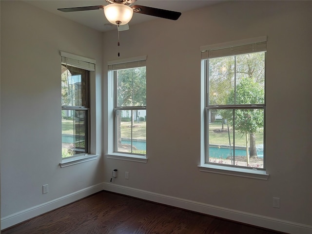 empty room featuring ceiling fan, baseboards, and dark wood-style flooring