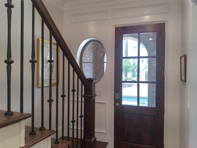 entrance foyer featuring stairs and crown molding