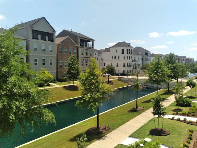 view of community featuring a water view, a residential view, and a yard