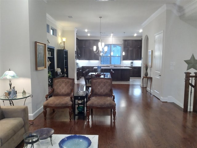 living area with arched walkways, a chandelier, baseboards, ornamental molding, and dark wood-style floors