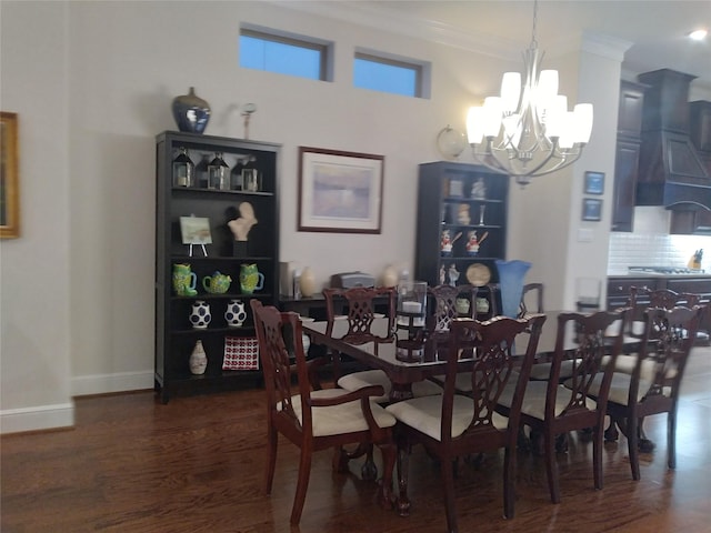 dining room featuring baseboards, ornamental molding, a chandelier, and wood finished floors