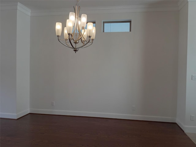 spare room with a notable chandelier, ornamental molding, dark wood finished floors, and baseboards