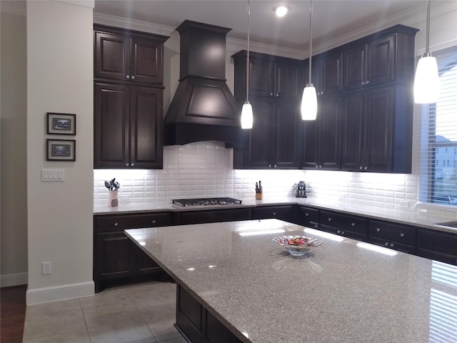 kitchen featuring tasteful backsplash, custom range hood, stainless steel gas cooktop, and light stone countertops