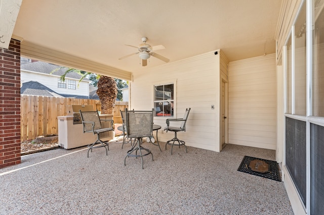 view of patio featuring outdoor dining area, fence, and a ceiling fan