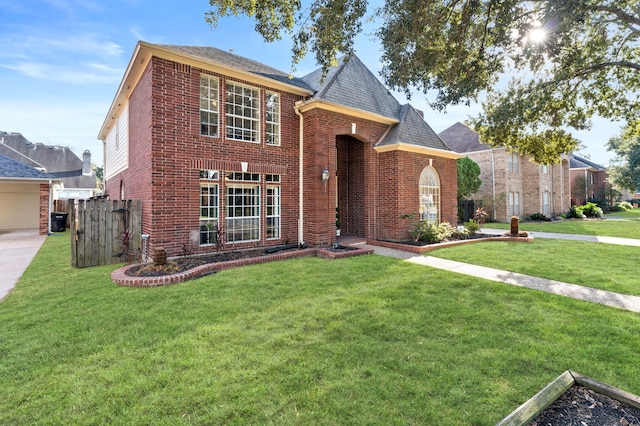 traditional-style home featuring brick siding, a front yard, and fence