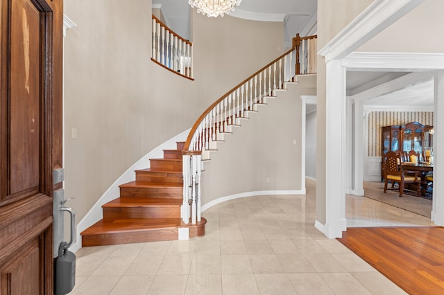 foyer entrance featuring a chandelier, stairway, baseboards, and crown molding