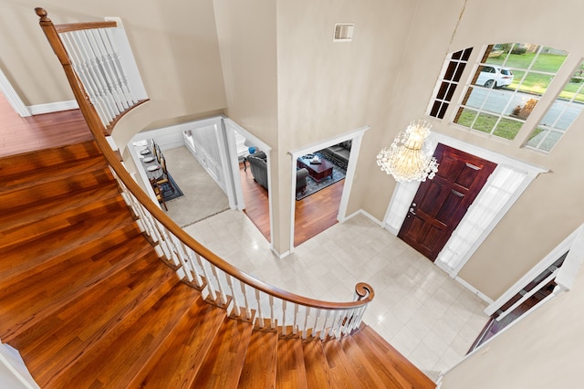 entrance foyer with a towering ceiling, an inviting chandelier, stairs, and wood finished floors